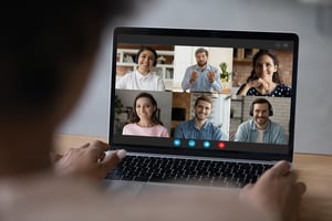 Person nimmt mit einem Laptop an einer Videokonferenz mit sechs Teilnehmenden teil