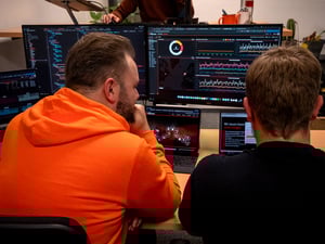 Zwei Menschen sitzen am Tisch und arbeiten gemeinsam an Bildschirmen